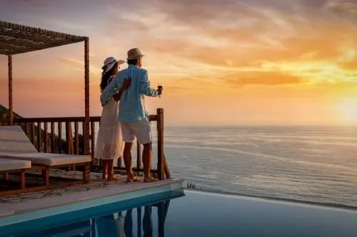 Paar blickt bei Sonnenuntergang vom Pooldeck auf das Meer