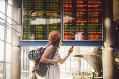 Reisende prüft die Abflugzeiten an der Anzeigetafel im Flughafen