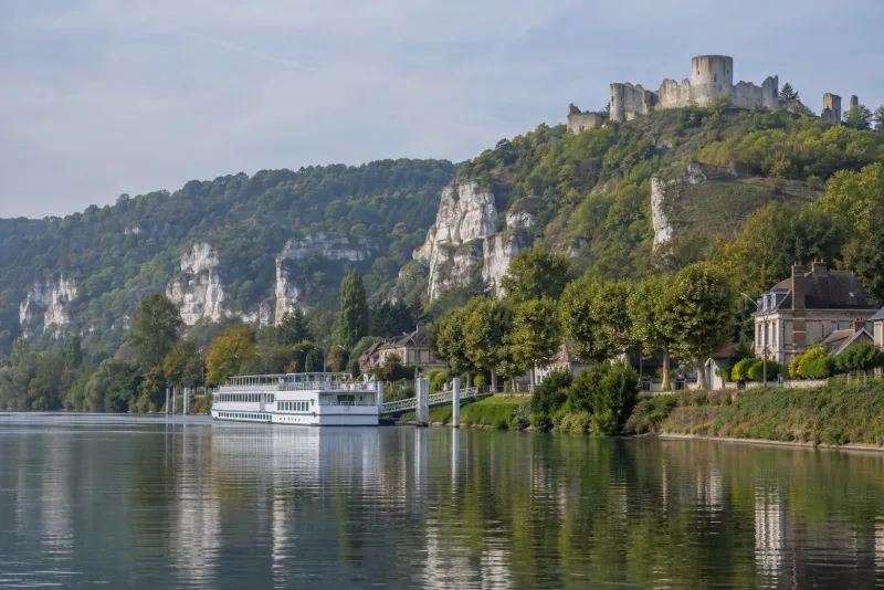 Flusskreuzfahrtschiff auf der Seine vor einem Dorf in der Normandie